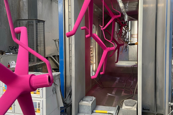 pink office chair feet going through a powder coating line highlighting the powder coating cost
